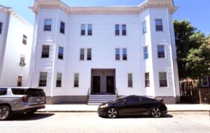 Exterior 10 Copeland, white three story buildings, stairs leading to entrance, parking in front of building.