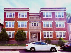 Exterior 34 Waumbeck street, 3 story brick building, white molding, parking on street.